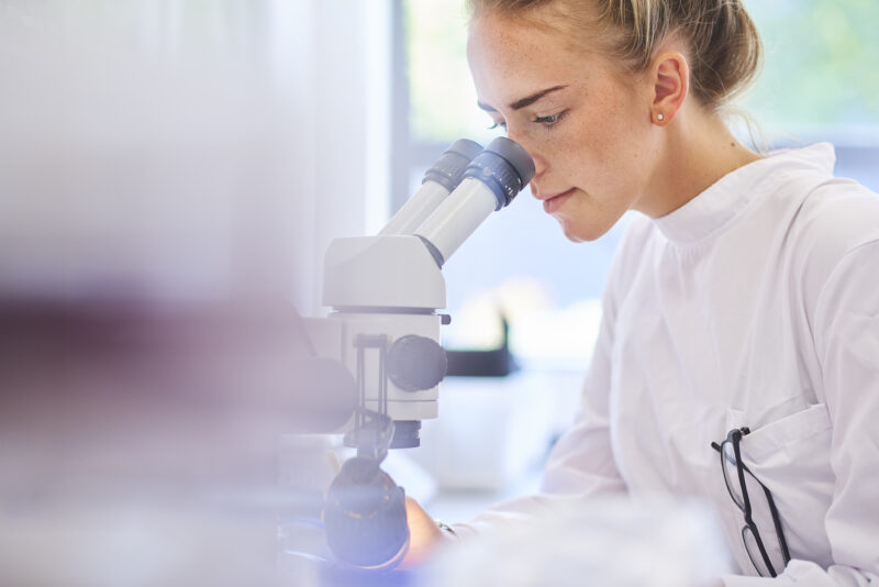 Chercheuse au microscope dans un laboratoire