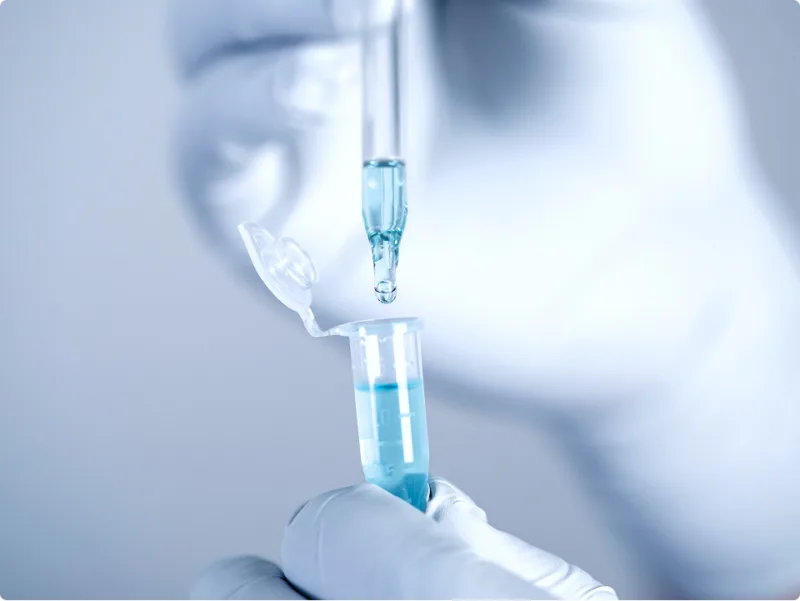 Pipette und Röhrchen mit blauer Flüssigkeit im Labor