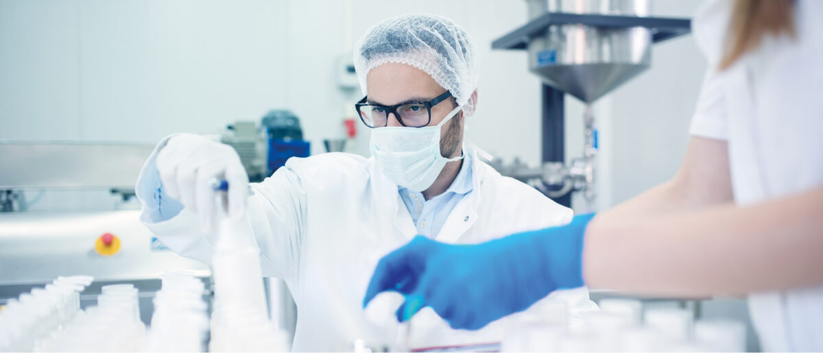 Forscher mit Haube und Mundschutz bei der Arbeit im Labor