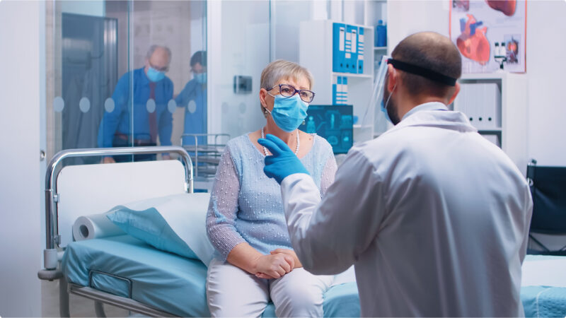 Arzt untersucht eine ältere Patientin im Spitalzimmer